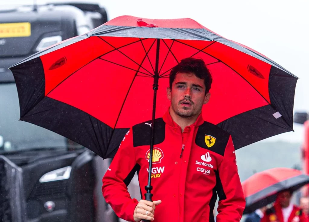 Charles Leclerc passeggia nel paddock a Spa con un ombrello sotto la pioggia